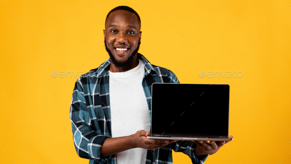 African Guy Showing Laptop Blank Screen On Yellow Background, Mockup