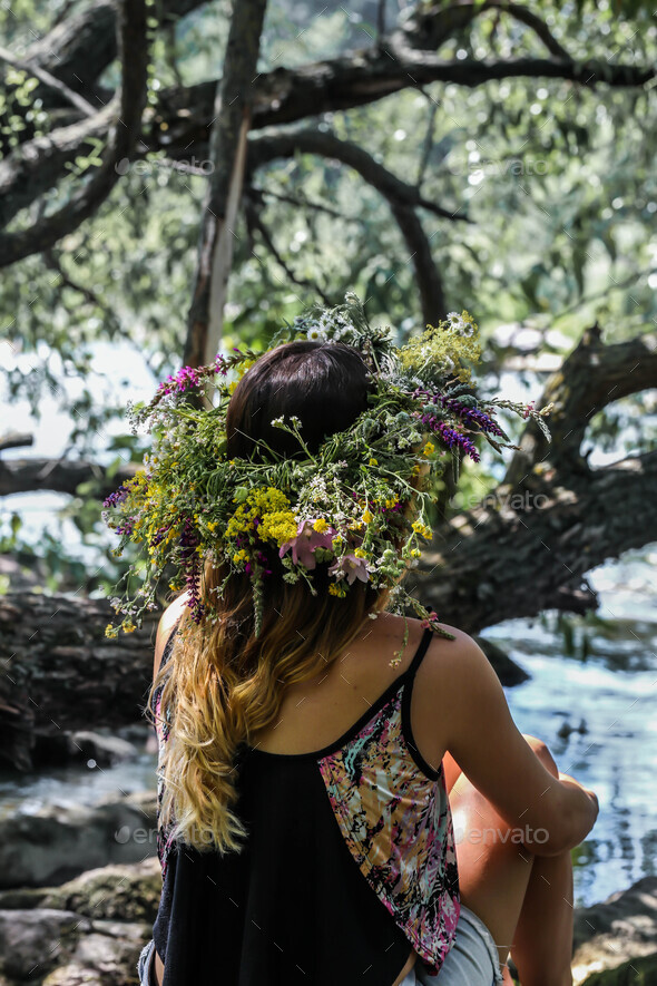 beautiful girl in a wreath of flowers on the banks the river, Sunny day.