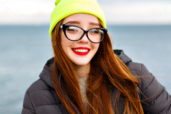 Redhead cute young hipster woman in stylish T-shirt in trendy sunglasses in  blue jeans poses