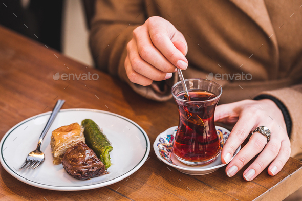 Traditional tea with turkish delights. Woman\'s hand stirs sugar