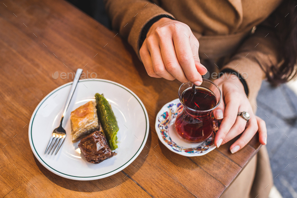 Traditional tea with turkish delights. Woman's hand stirs sugar