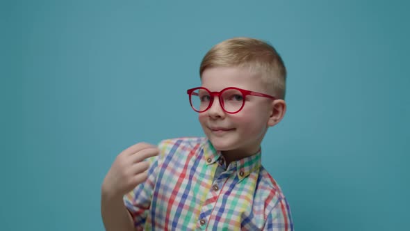 Cheerful Child Dancing and Looking at Camera on Blue Background in Slow Motion alt