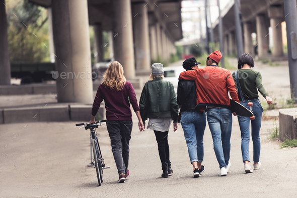 back view of young stylish people walking by industrial district