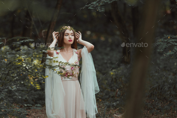 fantasy girl with elf ears in flower dress posing in forest