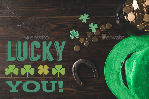 flat lay with horseshoe, hat and pot of gold on wooden tabletop with lucky you lettering