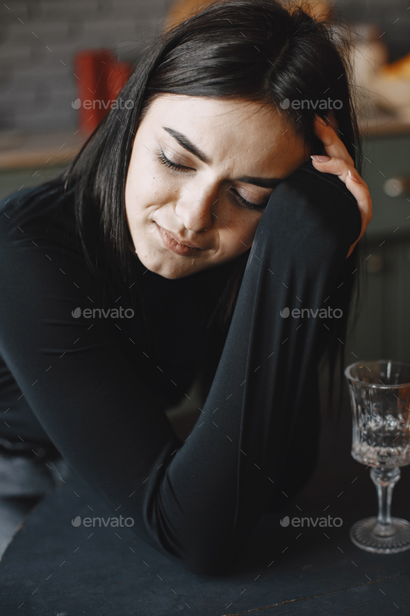 Depressed woman in black sweater crying in a kitchen