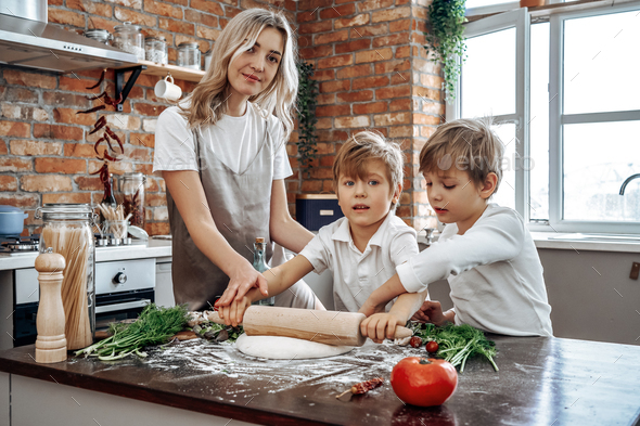 Family of mother and her two sons in kitchen they cook together