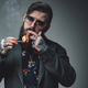 Styled and bearded hipster person with cuban cigar in gray
