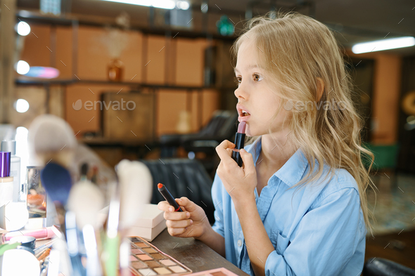 Little girl applies pomade in makeup salon