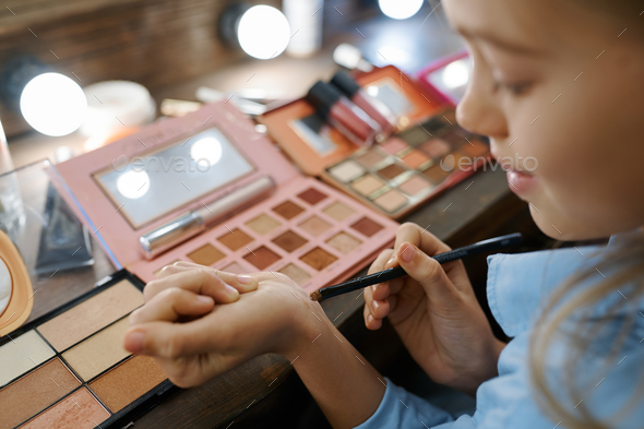 Little girl choosing shadows, makeup salon