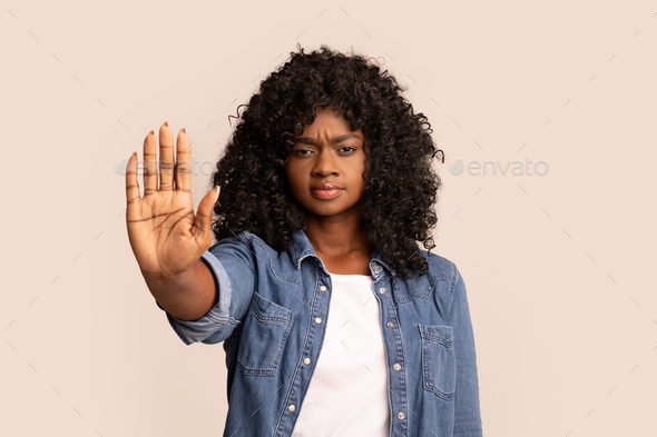 Serious black woman showing her palm, stop gesture