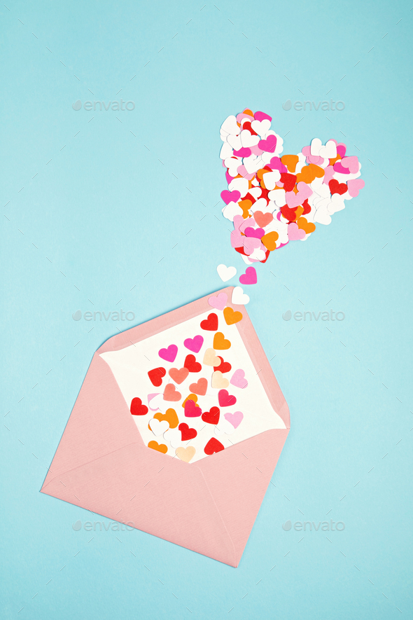 Pink envelope with heart shaped confetti over the blue background. Love, letter, message, saint