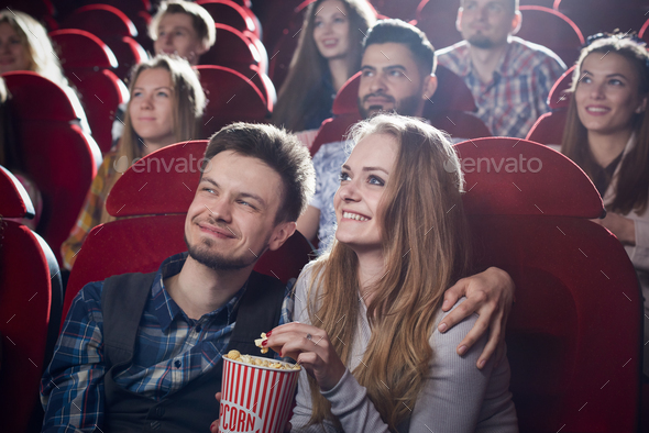 Couple sitting together in cinema, watching comedy