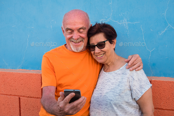 Smiling senior couple looking together at the same mobile phone ...