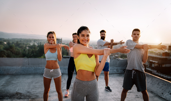 Group of cheerful fit fitness team exercising together outdoor