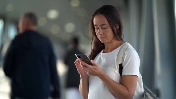 Woman Is Using Smartphone in Subway Underpass, Checking Social Nets and Surfing Internet alt