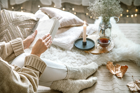 Cozy autumn at home, a woman with tea and a book.