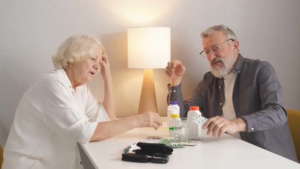 Elderly Couple Understands a Variety of Medicines Sitting in the Kitchen alt