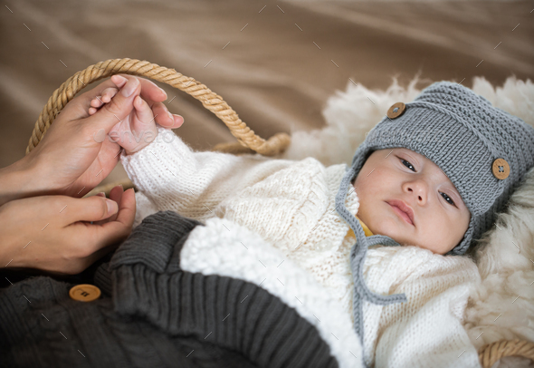 Cute portrait of a sleepy baby boy in a warm knitted hat.