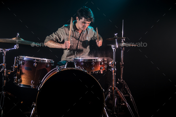 musician playing drums with splashes, black background with beautiful soft light