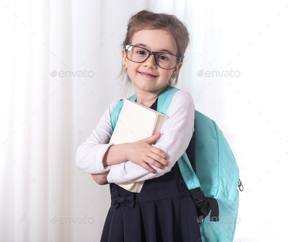 Girl-elementary school student with a backpack and a book Stock Photo by  puhimec
