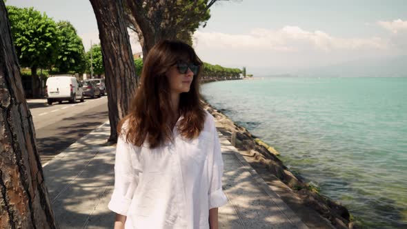 Real Time Shot of a Young Beautiful Girl Walking Along the Embankment of Lake Garda, Italy.