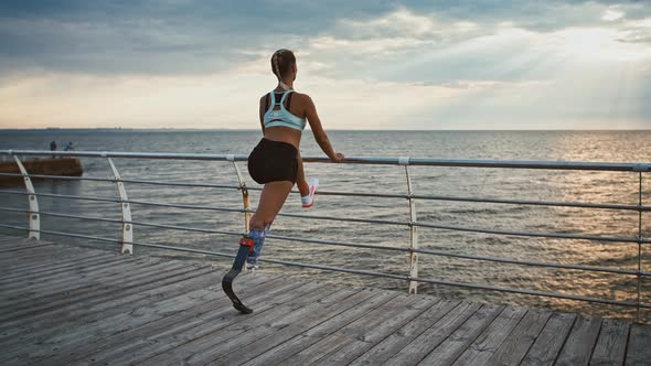 Disabled Girl Working Out on Pier Stretching and Enjoying Seaview alt