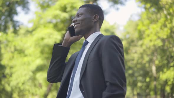 Portrait of Confident African American Man in Suit Talking on the Phone While Noticing Camera alt