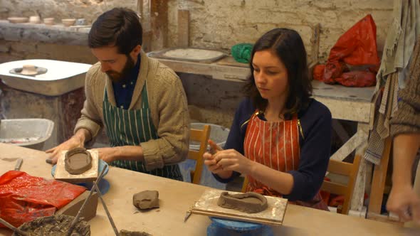 Male and female potters molding a clay alt