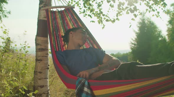 Relaxed Attractive Arab Male Tourist Napping in Hammock in Mountains at Daybreak alt