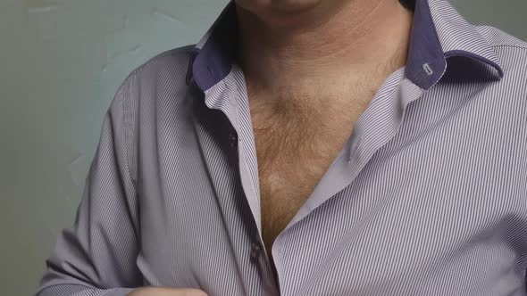 a Young and Mature Man with Chest Hair Takes Off His Shirt