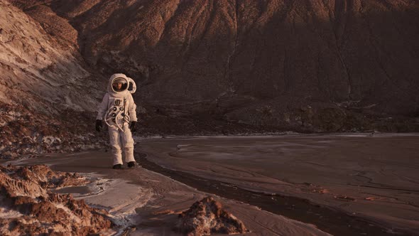 the Astronaut Walks Cautiously Along the Stream Raises His Hand alt