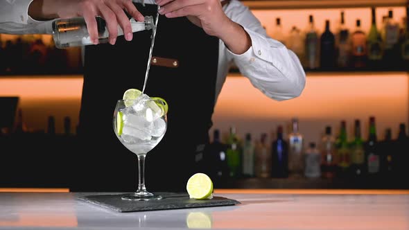 Bartender is Preparing a Delicious Cocktail Pouring Beverage Using a Cocktail Spoon alt