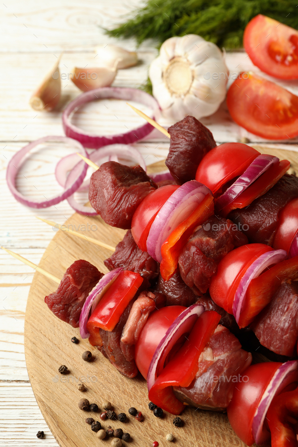 Download Cutting board with shish kebab and ingredients on wooden background Stock Photo by AtlasComposer