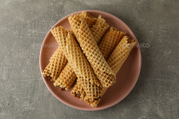 Plate with wafer rolls with condensed milk on gray background