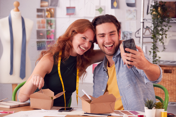 Male And Female Fashion Business Owners Eat Lunch Posing For Selfie On Mobile Phone In Studio
