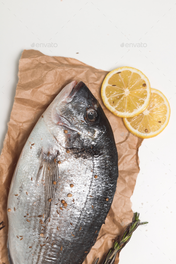 Raw dorada fish or gilt-head bream over white background, flat lay, top view - Stock Photo - Images