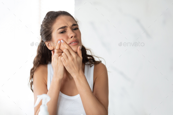 Frustrated Lady With Acne Problem Squeezing Pimple On Cheek Indoor