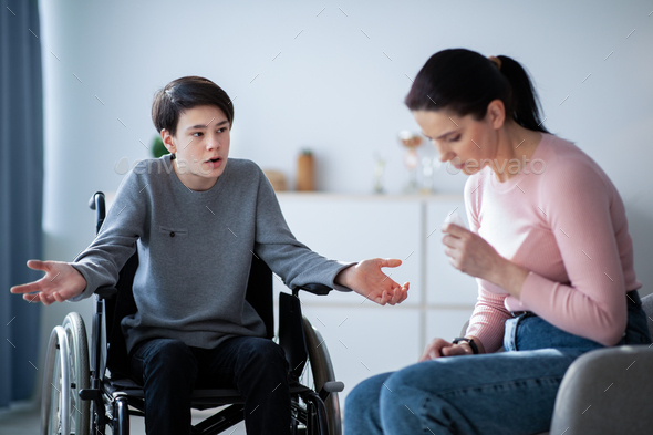 Family disagreement. Upset mother crying and her teenage son in wheelchair trying to justify himself