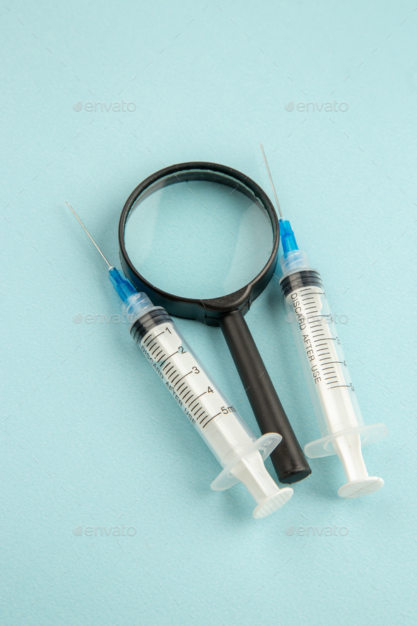 above view covid injections with magnifier on light blue background virus science drug covid