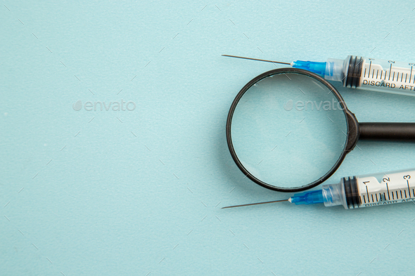 top view covid injections with magnifier on light blue background virus science drug covid pandemic