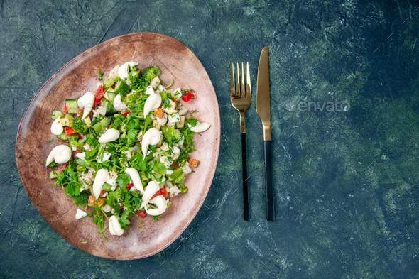 top view fresh vegetable salad inside elegant plate with cutlery on a dark blue background health