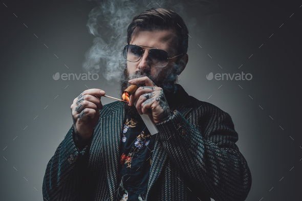 Styled and bearded hipster person with cuban cigar in gray background Stock  Photo by fxquadro