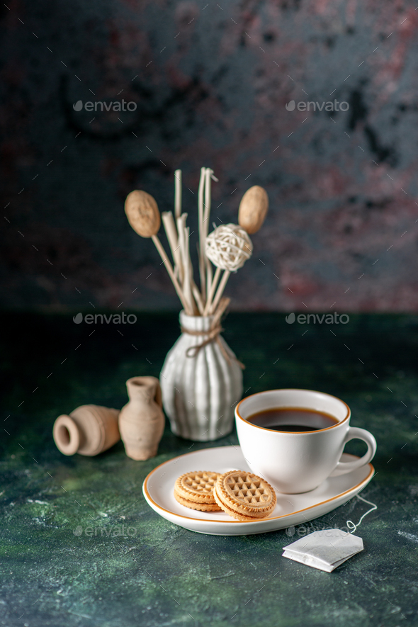 front view cup of tea with little sweet biscuits in white plate on dark ...