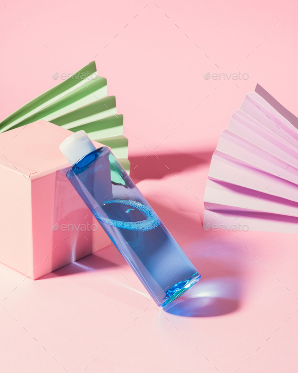 Blue skin care toner bottle on pink geometrical background