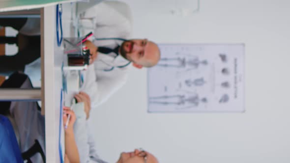Vertical Video Portrait of Elderly Doctor Standing in Front of Camera Smiling alt