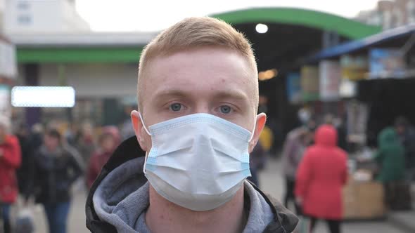 Guy Wearing Protective Mask From Virus Outdoor in the People Crowdy. Portrait of Young Man with alt
