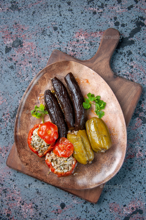 top view eggplant dolma with cooked tomatoes and bell-peppers filled with ground meat on blue