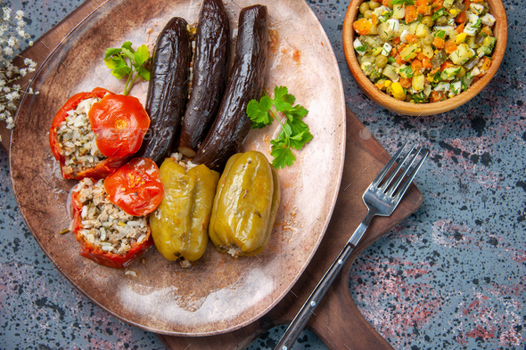 top view eggplant dolma with cooked tomatoes and bell-peppers filled with ground meat on blue