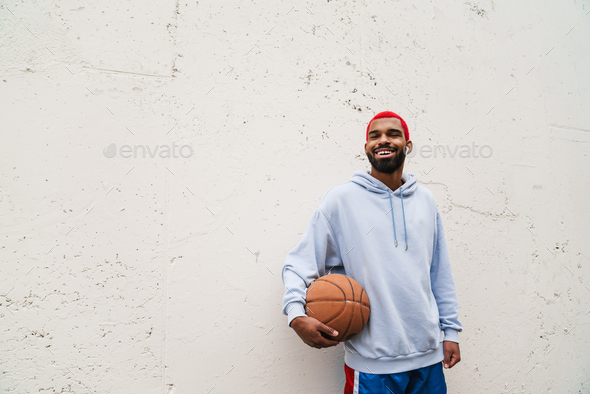 Smiling african american guy in earphones standing with basketball